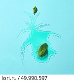 Abstract composition of melted ice cream on a blue glass background with mint leaves clear boundaries and reflection. Top view. Flat lay of a puddle of melted green mint ice cream with mint leaves on a blue glass background with reflection. Стоковое фото, агентство Ingram Publishing / Фотобанк Лори