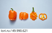 A set of different pieces and a whole ripe orange pepper with a green stem on a gray background. Vegetarian Healthy Food Concept. Top view. Juicy fresh pepper sliced and whole on a gray background. Top view. Стоковое фото, агентство Ingram Publishing / Фотобанк Лори