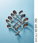 Pattern made of metal vintage spoons on a blue paper background top view. Cutlery set of silver tablespoon dessert spoon and tea spoon isolated on blue. Стоковое фото, агентство Ingram Publishing / Фотобанк Лори