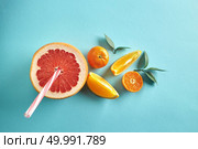 Vitamin drink from half a grapefruit, tangerine and slices of orange on with straws and leaves on a blue paper background top view. Dietic drink. Different citrus with straws and leaves on a blue paper background top view. Healthy drink. Стоковое фото, агентство Ingram Publishing / Фотобанк Лори