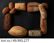 Different kinds of bread isolated on black background. Frame of loafs represented one after another. White and black bread with blank space in middle.. Different kinds of bread on background. Стоковое фото, агентство Ingram Publishing / Фотобанк Лори