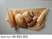 Assortment of different types of bread on paper on a gray background. Assortment of baked goods. Стоковое фото, агентство Ingram Publishing / Фотобанк Лори