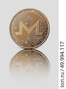 Crypto currency of Monero. Gold coin with reflection on white glossy background. Conceptual image for worldwide cryptocurrency and digital payment system.. Gold Monero coin is reflected on a white glossy background. Modern way of exchange. Стоковое фото, агентство Ingram Publishing / Фотобанк Лори