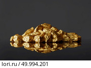 Close up of mound of gold nuggets on a black reflective surface background. Concept of financing and Noble metal. Mound of gold nuggets on a black reflective surface background. Стоковое фото, агентство Ingram Publishing / Фотобанк Лори