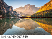 Beautiful Braies lake at sunrise in autumn in Dolomites, Italy. Landscape with mountains, gold sunlight, water with reflection, trees with orange leaves in fall morning. Travel in italian alps. Nature. Стоковое фото, агентство Ingram Publishing / Фотобанк Лори