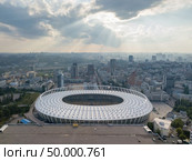 KIEV, UKRAINE - July 19, 2018. Aerial view from drone to a city landscape and National Olimpic Complex in Kiev, Ukraine at sunset on a background cloudy sky in a summer day.. KYIV, UKRAINE - July 19, 2018. National Sports Complex Olympic, stadium NSC Olimpiysky. Panoramic viev from drone of cityscape and the stadium. Редакционное фото, агентство Ingram Publishing / Фотобанк Лори