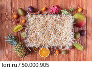 A variety of tropical organic fruits presented around a wooden empty box on a brown wooden table with space for text. Flat lay. Set of different exotic fruits around an empty wooden box on a brown wooden background with copy space. Flat lay. Стоковое фото, агентство Ingram Publishing / Фотобанк Лори