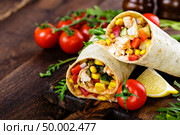 Burritos wraps with chicken meat and vegetables on wooden background. Стоковое фото, агентство Ingram Publishing / Фотобанк Лори