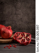 Ripe pomegranate fruit and pomegranate seeds on dark background, close-up. Healthy vegetarian antioxidant organic diet food. Стоковое фото, агентство Ingram Publishing / Фотобанк Лори