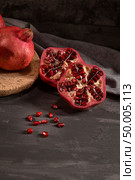 Ripe pomegranate fruit and pomegranate seeds on dark background, close-up. Healthy vegetarian antioxidant organic diet food. Стоковое фото, агентство Ingram Publishing / Фотобанк Лори