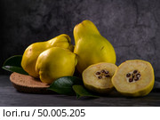 Ripe yellow quinces or queen apple fruits and sliced quince halves with seeds in craft cork plates on black rustic background. Стоковое фото, агентство Ingram Publishing / Фотобанк Лори