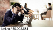 Portrait of Asian Businessman strain and got pressured after see data in smart phone and laptop and fail for his work in cafe with business team in background using for coporate background work, panoramic web banner composition. Стоковое фото, агентство Ingram Publishing / Фотобанк Лори