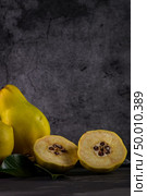 Ripe yellow quinces or queen apple fruits and sliced quince halves with seeds in craft cork plates on black rustic background. Стоковое фото, агентство Ingram Publishing / Фотобанк Лори