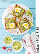Toasts with avocado guacamole, fresh radish, boiled egg, chia and pumpkin seeds. Diet breakfast. Delicious and healthy plant-based food. Flat lay. Top view. Стоковое фото, агентство Ingram Publishing / Фотобанк Лори