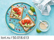 Toasts with feta cheese, tomatoes, avocado, pomegranate, pumpkin seeds and flaxseed sprouts. Diet breakfast. Delicious and healthy food. Flat lay. Top view. Стоковое фото, агентство Ingram Publishing / Фотобанк Лори