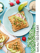 Toasts with chickpea hummus, avocado, fresh radish, cucumber, sesame seeds and flaxseed sprouts. Diet breakfast. Delicious and healthy plant-based vegetarian, vegan food. Flat lay. Top view. Стоковое фото, агентство Ingram Publishing / Фотобанк Лори