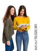 Studio portrait of two beautiful girls holding and showing something on a tablet. Стоковое фото, агентство Ingram Publishing / Фотобанк Лори