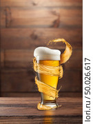 A glass of cold beer with drops and froth around a splash on a dark wooden background with copy space.. A glass of fresh beer with foam and a splash on a dark wooden background with copy space. Стоковое фото, агентство Ingram Publishing / Фотобанк Лори