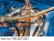 Aerial view of road in the modern city at night in winter. Top view of traffic in highway junction with illumination. Elevated road and interchange overpass. Busy intersection. Expressway and motorway. Стоковое фото, агентство Ingram Publishing / Фотобанк Лори