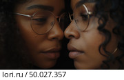 Two women with curly hair and glasses intimately lean close, their faces almost touching, expressing a close bond. Стоковое AI-изображение, AI-художник Данила Большаков / Фотобанк Лори