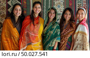 A group of smiling women wearing colorful saris and scarves representing diverse Indian fabrics and patterns. Стоковое AI-изображение, AI-художник Данила Большаков / Фотобанк Лори