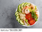 Hawaiian poke bowl with shrimps, rice and vegetables, healthy Buddha bowl with prawns, rice, avocado, cucumber, tomato and lettuce. Top view. Стоковое фото, агентство Ingram Publishing / Фотобанк Лори