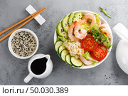 Hawaiian poke bowl with shrimps, rice and vegetables, healthy Buddha bowl with prawns, rice, avocado, cucumber, tomato and lettuce. Top view. Стоковое фото, агентство Ingram Publishing / Фотобанк Лори