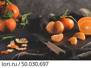 Fresh mandarin oranges or tangerines with leaves on textured dark background. Стоковое фото, агентство Ingram Publishing / Фотобанк Лори