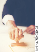Close-up Of A Person’s Hand Stamping With Approved Stamp On Document At Desk. Стоковое фото, агентство Ingram Publishing / Фотобанк Лори