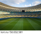 Birds eye view from drone blue-yellow stands and a green field stadium on a summer day against a blue sky.. Green field with blue-yellow stands against the blue sky with clouds. Photo from drone. Редакционное фото, агентство Ingram Publishing / Фотобанк Лори
