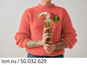 Congratulation bouquet of flowers Ranunculus is holding a girl with a tattoo on a gray background.Trend color of the year 2019 Living Coral Pantone. Postcards for Mother’s Day.. A beautiful bouquet of flowers of a Ranunculus in a girl’s hands with tatoo on a gray background. Trend color of the year 2019 Living Coral Pantone. Place for text. Стоковое фото, агентство Ingram Publishing / Фотобанк Лори