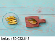 Preparation of fruit salad from sliced fresh exotic fruits on a wooden board, womans hands mix a salad with cream in a glass bowl on a blue wooden background. Flat lay.. Sliced ripe fresh mango fruit, avocado, pomegranate, orange on a wooden board and cooking fruit salad with cream female hands in a glass bowl on a blue wooden background. Stop motion animation. Стоковое фото, агентство Ingram Publishing / Фотобанк Лори