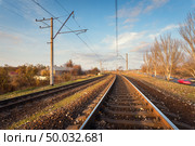 Railroad against beautiful sky at sunset. Industrial landscape with railway station, colorful blue sky, trees and grass, cars in motion. Railway junction. Heavy industry. Railways. Cargo shipping. Стоковое фото, агентство Ingram Publishing / Фотобанк Лори