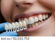 Close-up of woman smiling while dentist compares teeth shades with color guide. Healthy white smile. Cosmetic dentistry. Professional dental care. Clean, natural look. Oral health concept. Banner. Стоковое AI-изображение, AI-художник Евгений Демидюк / Фотобанк Лори