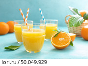 Orange freshly squeezed juice in glass and fresh fruits on a blue vivid background. Стоковое фото, агентство Ingram Publishing / Фотобанк Лори