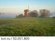 View of an ancient wooden windmill on the banks of the Sorot River on a foggy summer morning, Mikhailovskoye, Pushkinskiye Gory, Pskov region, Russia. Стоковое фото, фотограф Ula Ulachka / Фотобанк Лори