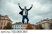 Dynamic urban leap professional man in midair triumph against a cityscape backdrop. Стоковое AI-изображение, AI-художник Андрей Бакусов / Фотобанк Лори