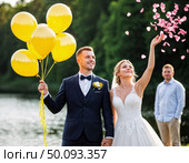 Счастливые молодожены на свадьбе у озера, выбрасывающие цветочные лепестки и держащие жёлтые шары. Стоковое AI-изображение, AI-художник Сергей Никифоров-Гордеев / Фотобанк Лори