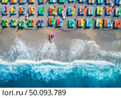 Aerial view of lying woman with swim ring in the sea in Oludeniz, Turkey. Summer seascape with girl, azure water, waves and sandy beach with colorful chaise-lounges in sunny day. Top view from drone . Aerial view of lying woman with swim ring in the sea. Стоковое фото, агентство Ingram Publishing / Фотобанк Лори