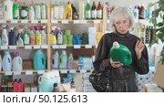Positive elderly woman consumer with household chemical products for washing indoors. Стоковое видео, видеограф Яков Филимонов / Фотобанк Лори