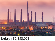 City buildings on the background of steel factory with smokestacks at night.  Metallurgical plant with chimney. steelworks, iron works. Heavy industry. Air pollution, smog. Industrial landscape. Стоковое фото, агентство Ingram Publishing / Фотобанк Лори