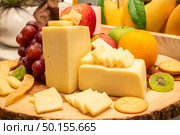 edam cheese with variety of fruit and cracker on wooden plate in buffet line. Стоковое фото, агентство Ingram Publishing / Фотобанк Лори