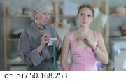 Careful old tailoress taking body sizes of young female client in tailor's shop. Стоковое видео, видеограф Яков Филимонов / Фотобанк Лори