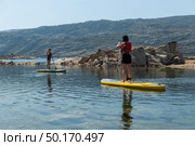 Stand up paddleboarding on lake. Watersport on lake. Tourist outdoor activity at Lagoa Comprida, Serra da Estrela National Park in Portugal. Стоковое фото, агентство Ingram Publishing / Фотобанк Лори