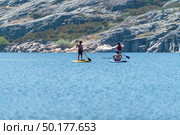 Stand up paddleboarding on lake. Watersport on lake. Tourist outdoor activity at Lagoa Comprida, Serra da Estrela National Park in Portugal. Стоковое фото, агентство Ingram Publishing / Фотобанк Лори