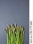 Fresh raw asparagus for cooking vegetarian food on a gray background with copy space. Top view. Vegan healthy nutrition concept.. Heap of fresh natural asparagus on a gray background. Стоковое фото, агентство Ingram Publishing / Фотобанк Лори
