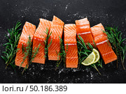 Salmon. Fresh raw salmon fish fillet with cooking ingredients, herbs and lemon on black background, top view. Стоковое фото, агентство Ingram Publishing / Фотобанк Лори