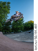 Biker jump high from jump box ramp performing big air trick. Стоковое фото, агентство Ingram Publishing / Фотобанк Лори