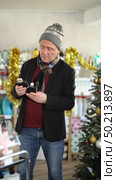In X mas atmosphere, senior man sniffs fragrance of perfume, chooses scent spray with pleasant smell. Стоковое видео, видеограф Яков Филимонов / Фотобанк Лори