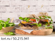 Healthy vegan burger with fresh vegetables and yogurt sauce on rustic kitchen counter top. Стоковое фото, агентство Ingram Publishing / Фотобанк Лори